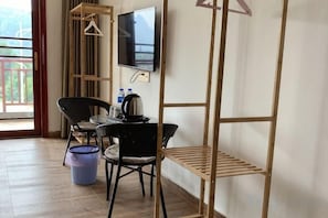 A room with a table, chairs, a TV, a shelf, and a window. - A Rest in Xinchang (Xinchang)