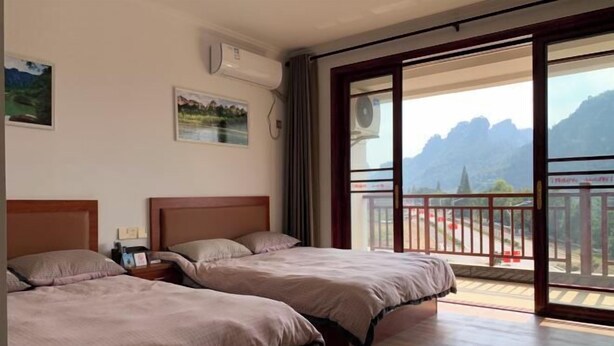 A hotel room with two beds, a balcony with a mountain view, and a large window. - A Rest in Xinchang (Xinchang)