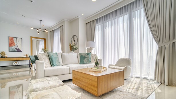 Ein modernes Wohnzimmer mit einer Couch, einem Couchtisch aus Holz und einem Glastisch.
