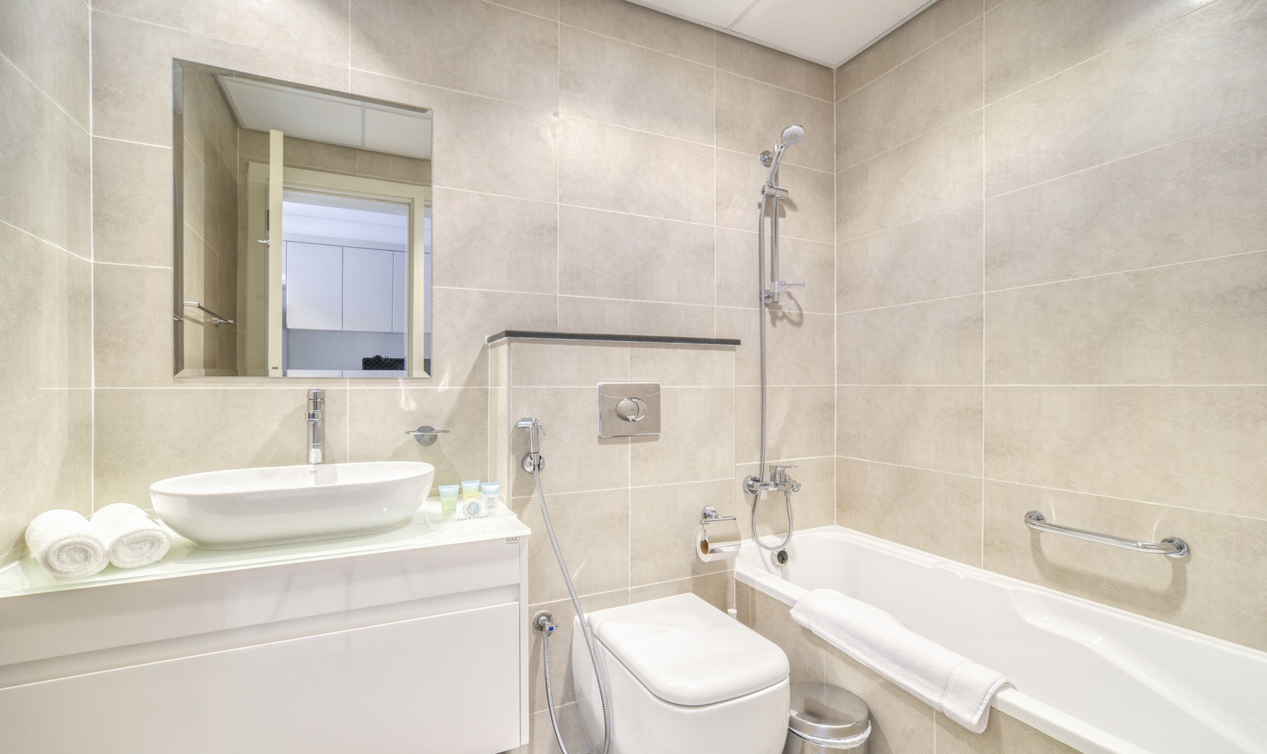 A modern bathroom with a large white bathtub, a sink with a mirror above it, and a shower area.