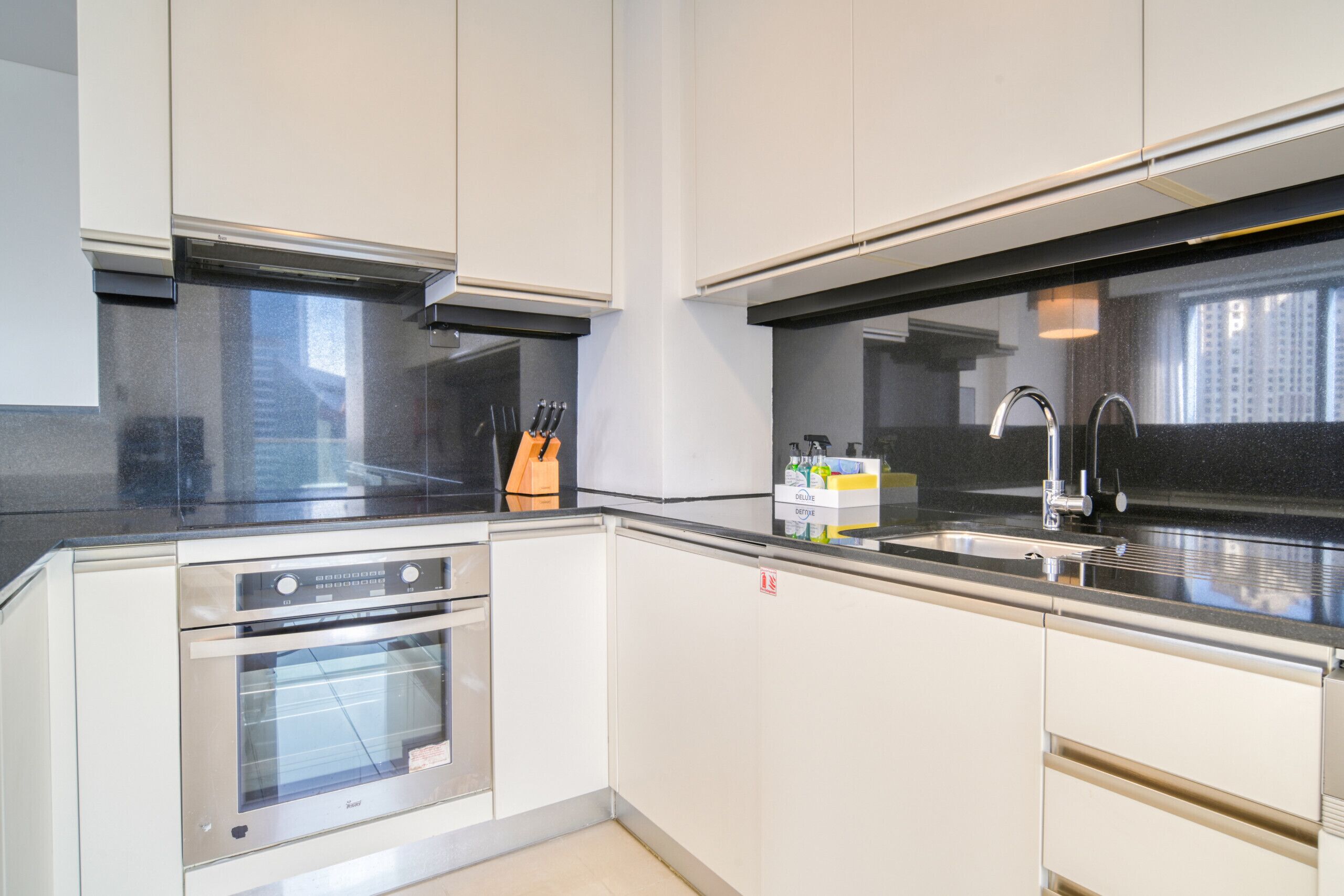 Une cuisine moderne dotée d’appareils électroménagers en acier inoxydable, d’un plan de travail noir et de meubles blancs.