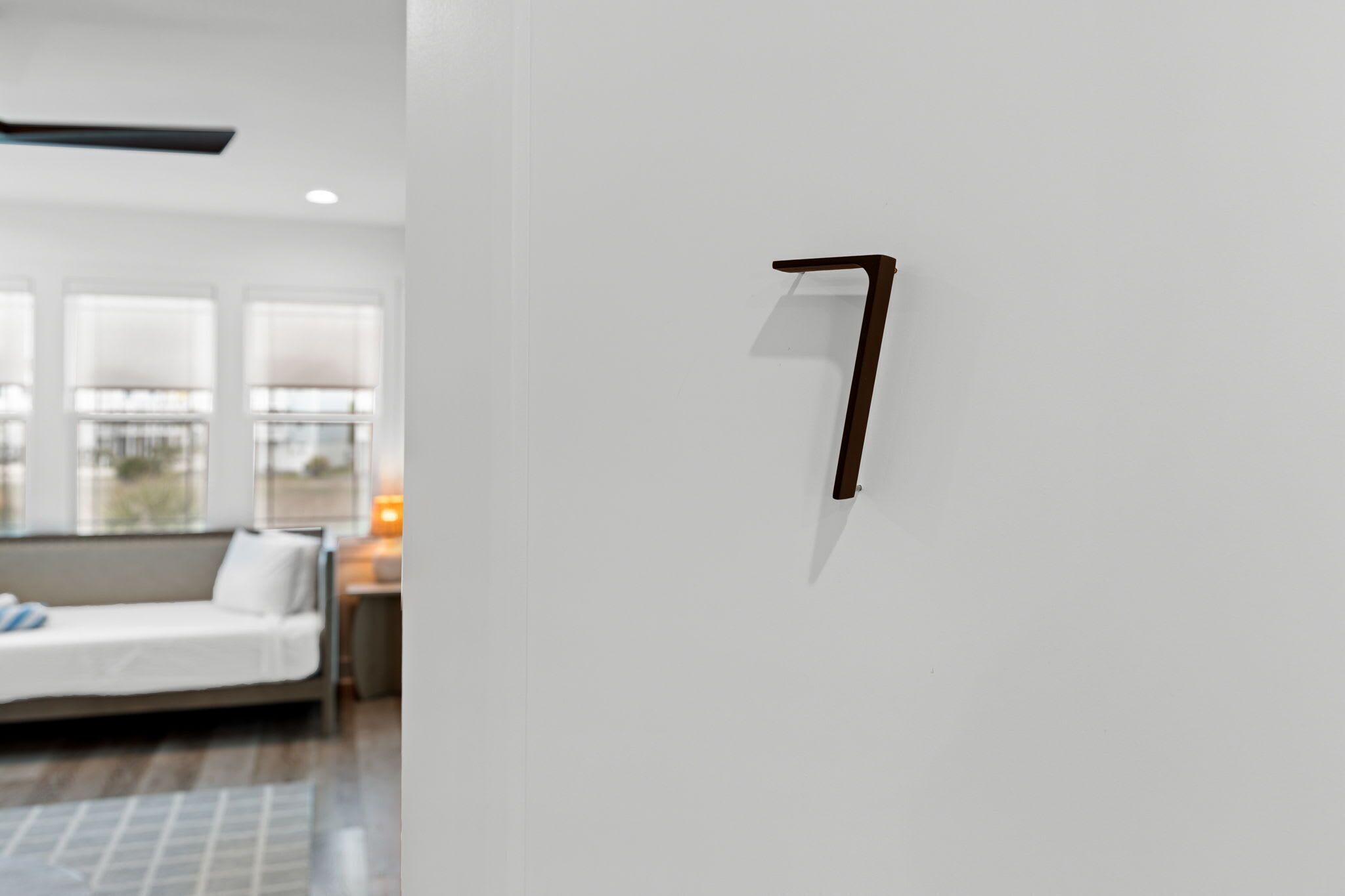 Un interior moderno con diseño minimalista, que presenta una pared blanca, un estante de madera oscura y un sofá blanco al fondo.