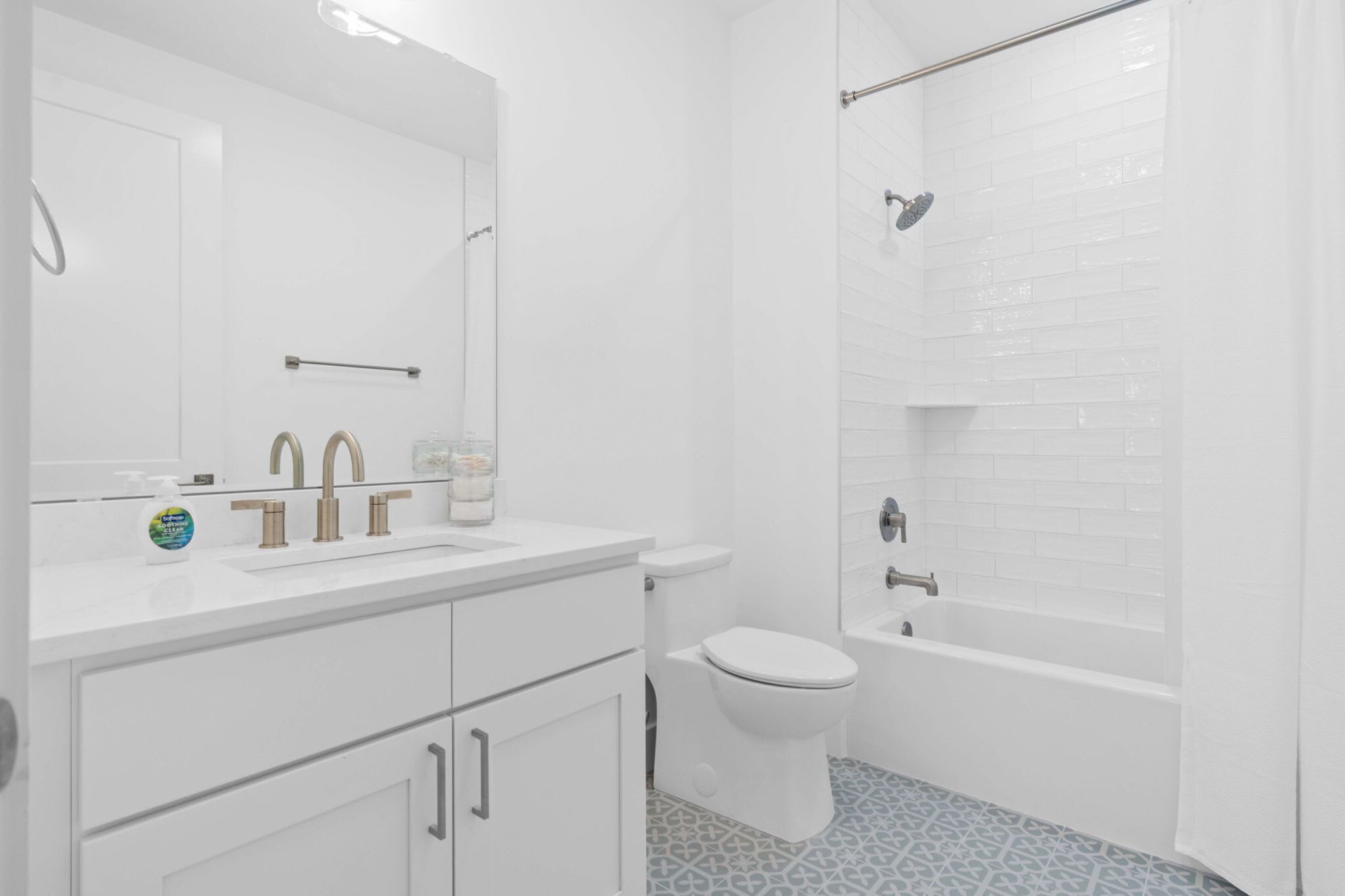Une salle de bain moderne avec un lavabo blanc, deux robinets, des toilettes et une baignoire.