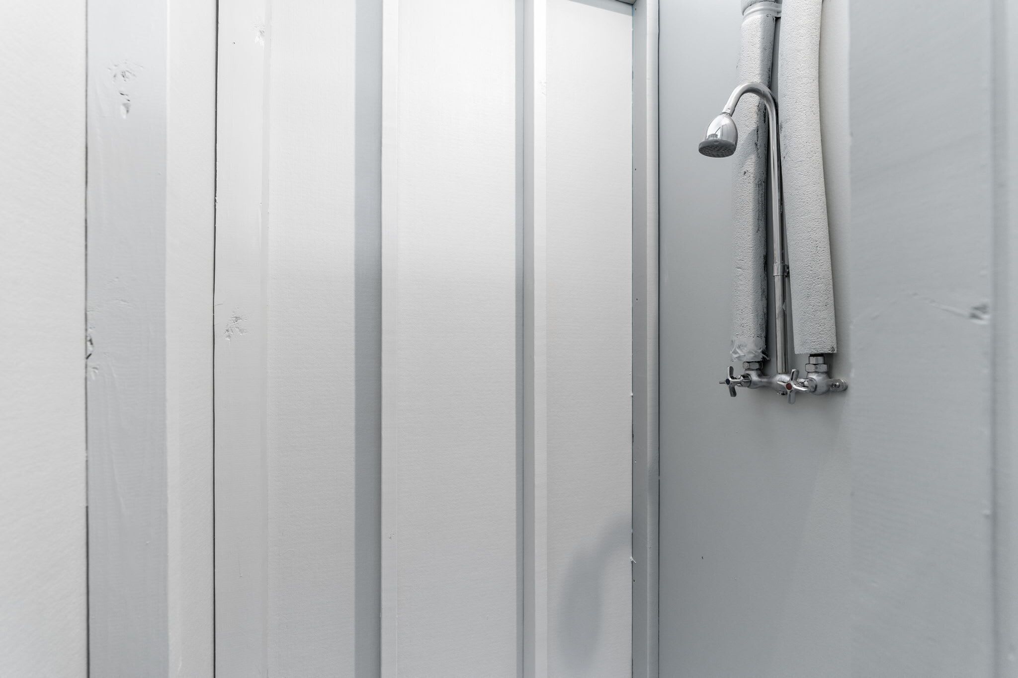 Eine weiße Dusche mit Handbrause und Handtuchhalter.