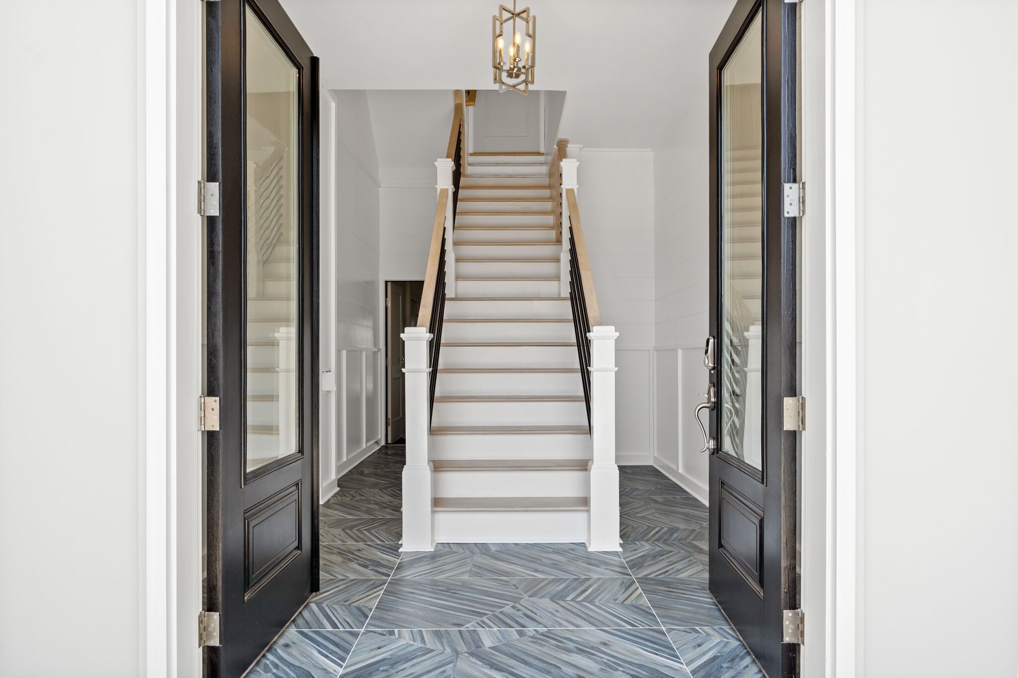 A staircase with white balusters and a wooden handrail, leading to a landing with a light fixture.