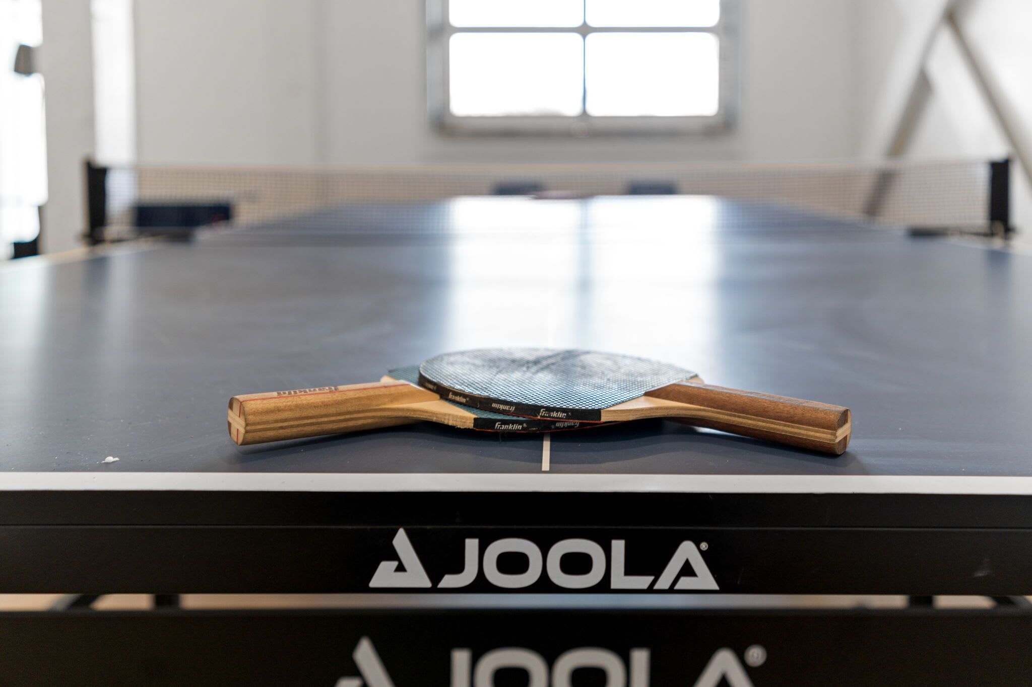 A table tennis table with a paddle and a book titled "Franklin" on it.