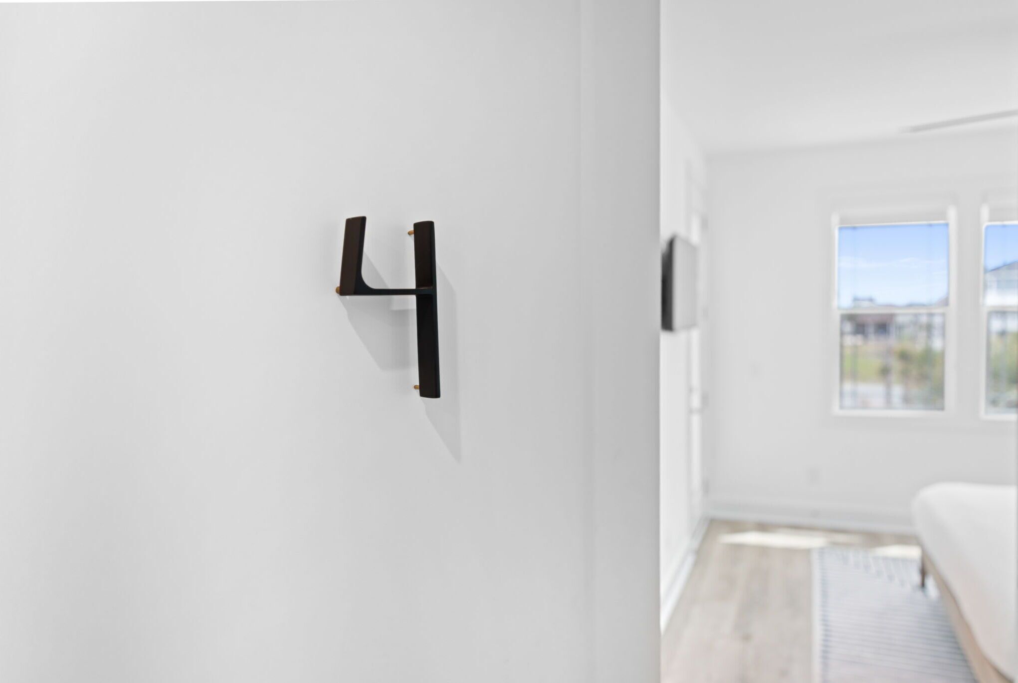 Une chambre moderne au design minimaliste, avec un mur blanc et un objet noir suspendu.