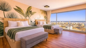 Une chambre moderne avec deux lits, un balcon offrant une vue sur la ville et une grande fenêtre.