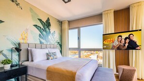 Une chambre d’hôtel moderne avec un grand lit, un téléviseur fixé au mur et une vue sur la ville.