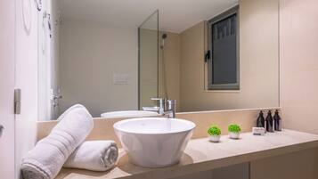 Un baño moderno con un lavamanos grande, dos espejos y una ducha.
