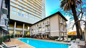 Un hôtel doté d’une piscine, d’un espace extérieur aménagé et d’un bâtiment à plusieurs étages avec des balcons.