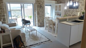 A modern kitchen with white cabinets, a dining area with a round table and chairs, and a cozy living space with a sofa and a coffee table. - Cosy town house 2* in Carnac (Carnac)