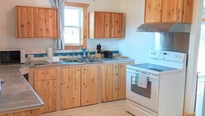A kitchen with wooden cabinets, a built-in oven, and a sink. - Red Barn Bed & Breakfast (Lunenburg)