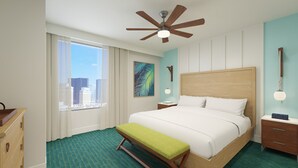 A hotel room with a large bed, a bench, a ceiling fan, a nightstand, a dresser, a window with curtains, a painting, and a city view. - 3BD/Vegas - Kitchen, Margarita Mixer, and Parking! (Las Vegas)