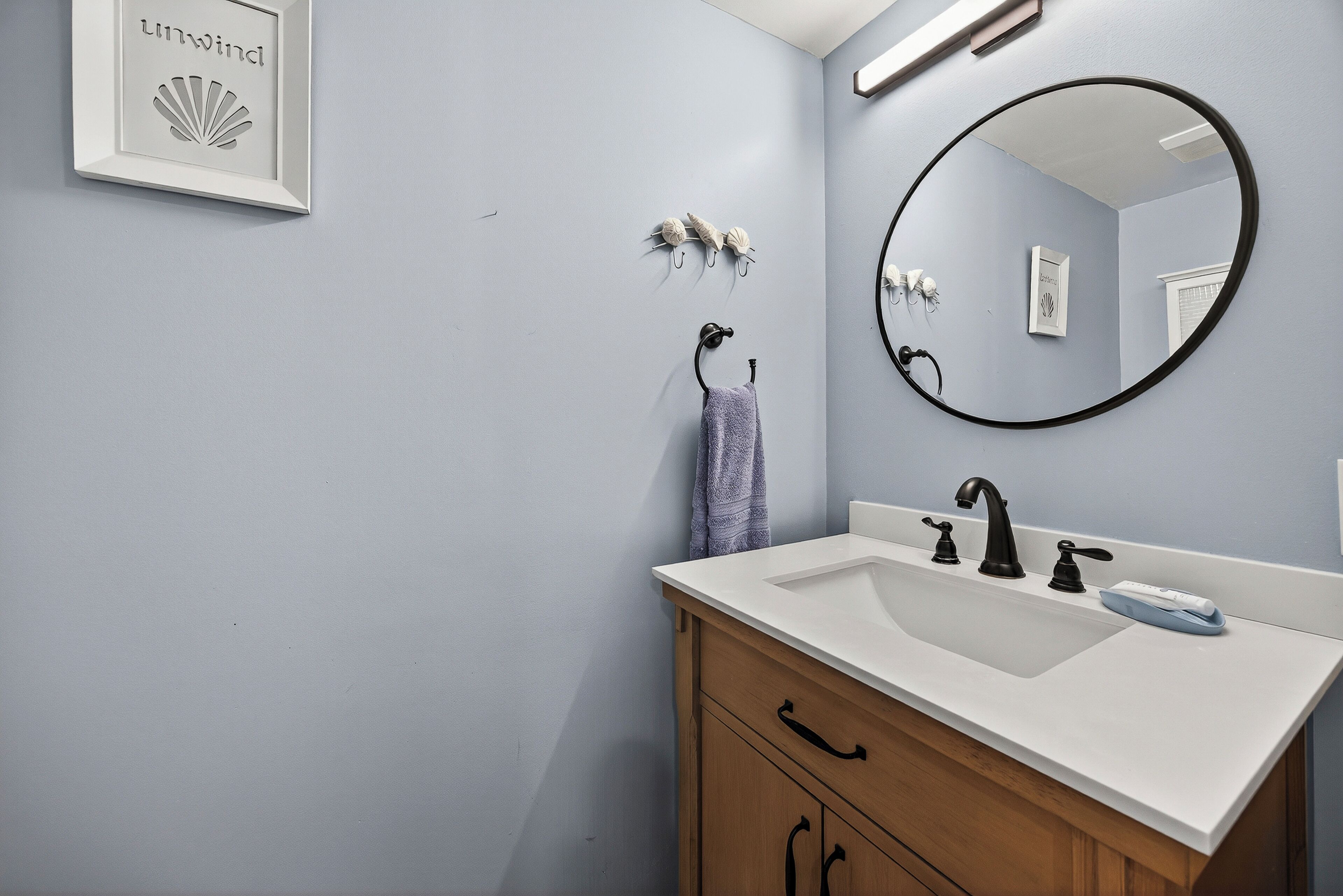 Un bagno con un lavandino bianco, un armadietto in legno e uno specchio.
