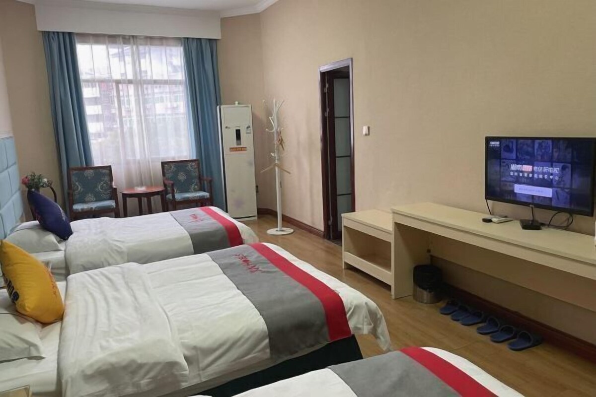 A hotel room with two beds, a desk with a television, a small table, and a chair.