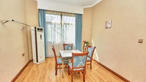A dining area with a table and chairs, a window with curtains, and a wall-mounted air conditioner. - Lezhi Hotel (Hengyang Hengshan Scenic Area Entrance) (Hengyang)