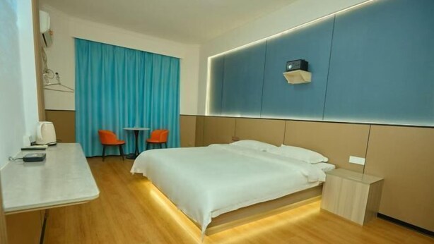 A hotel room with a bed, bedside table, and a desk with chairs. - Lezhi Hotel (Hengyang Hengshan Scenic Area Entrance) (Hengyang)