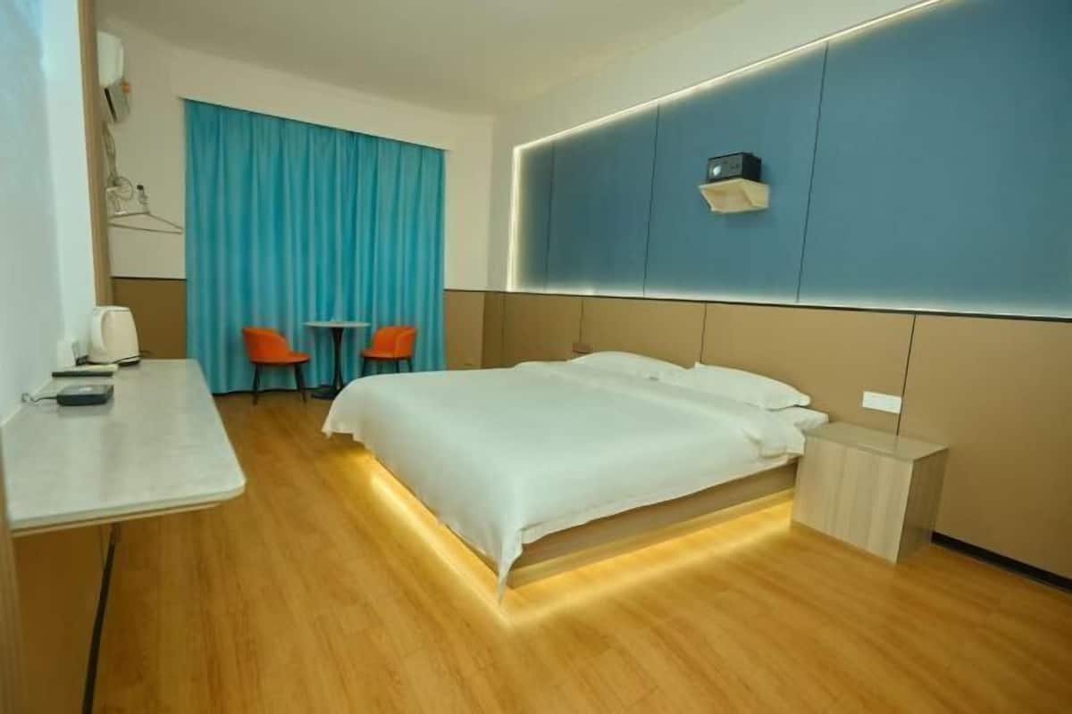 A hotel room with a bed, bedside table, and a desk with chairs.