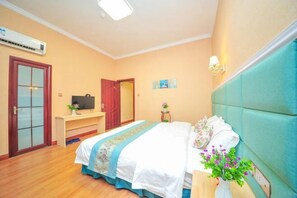 A bedroom with a bed, bedside table, and a desk with a chair. There is a door and an air conditioning unit on the wall. - Lezhi Hotel (Hengyang Hengshan Scenic Area Entrance) (Hengyang)