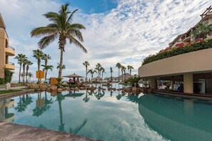 A resort pool with palm trees and a clear sky. - Beachfront, Direct Ocean View, 5 Star (Cabo San Lucas)