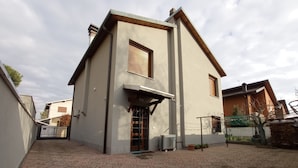 Een moderne, twee verdiepingen tellende woning met een betegeld terras ervoor.