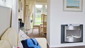 Ein modernes Wohnzimmer mit Glastisch, Kamin und Blick auf den Garten.