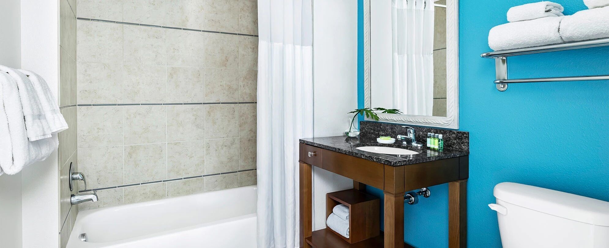 A bathroom with a bathtub, a sink with a mirror, and a toilet.