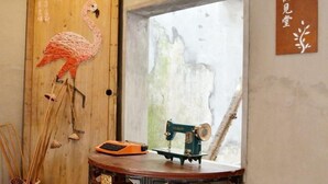 Une pièce avec une porte en bois ornée d’un motif de flamant rose, une machine à coudre posée sur une petite table et un mur sur lequel est accroché un panneau.