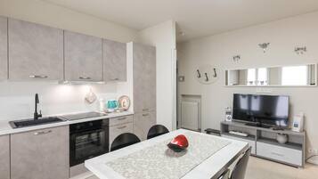 Una cucina moderna con zona pranzo, una TV a schermo piatto e un oggetto rosso sul tavolo.