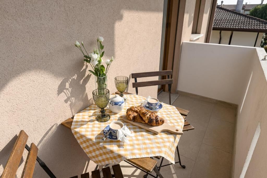 Una mesa con mantel a cuadros, un jarrón con flores, un croissant y tazas de té.