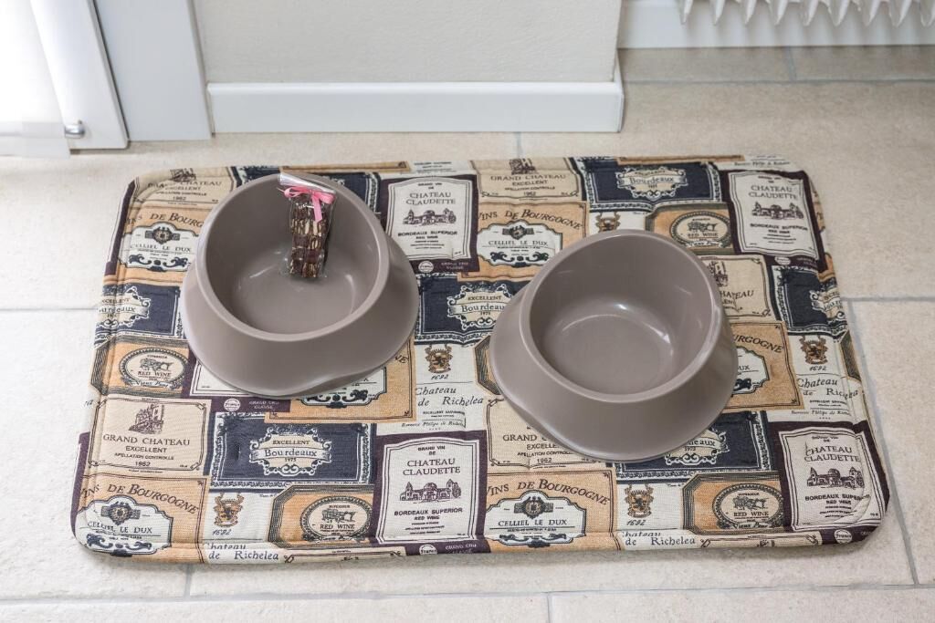 Un plateau avec deux bols posés sur une nappe ornée d’étiquettes de bouteilles de vin anciennes.