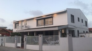 Un immeuble de deux étages doté d’un balcon, d’une entrée sécurisée par un portail et d’un garage visible.