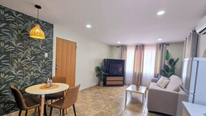 Ein Wohnzimmer mit Essbereich, einer Couch, einem Fernseher und einem Kühlschrank.