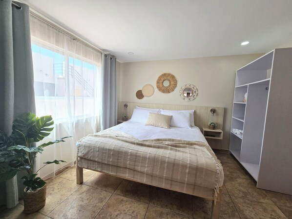 Une chambre à coucher bien rangée, avec un lit, des tables de chevet, une armoire et des miroirs décoratifs sur les murs.