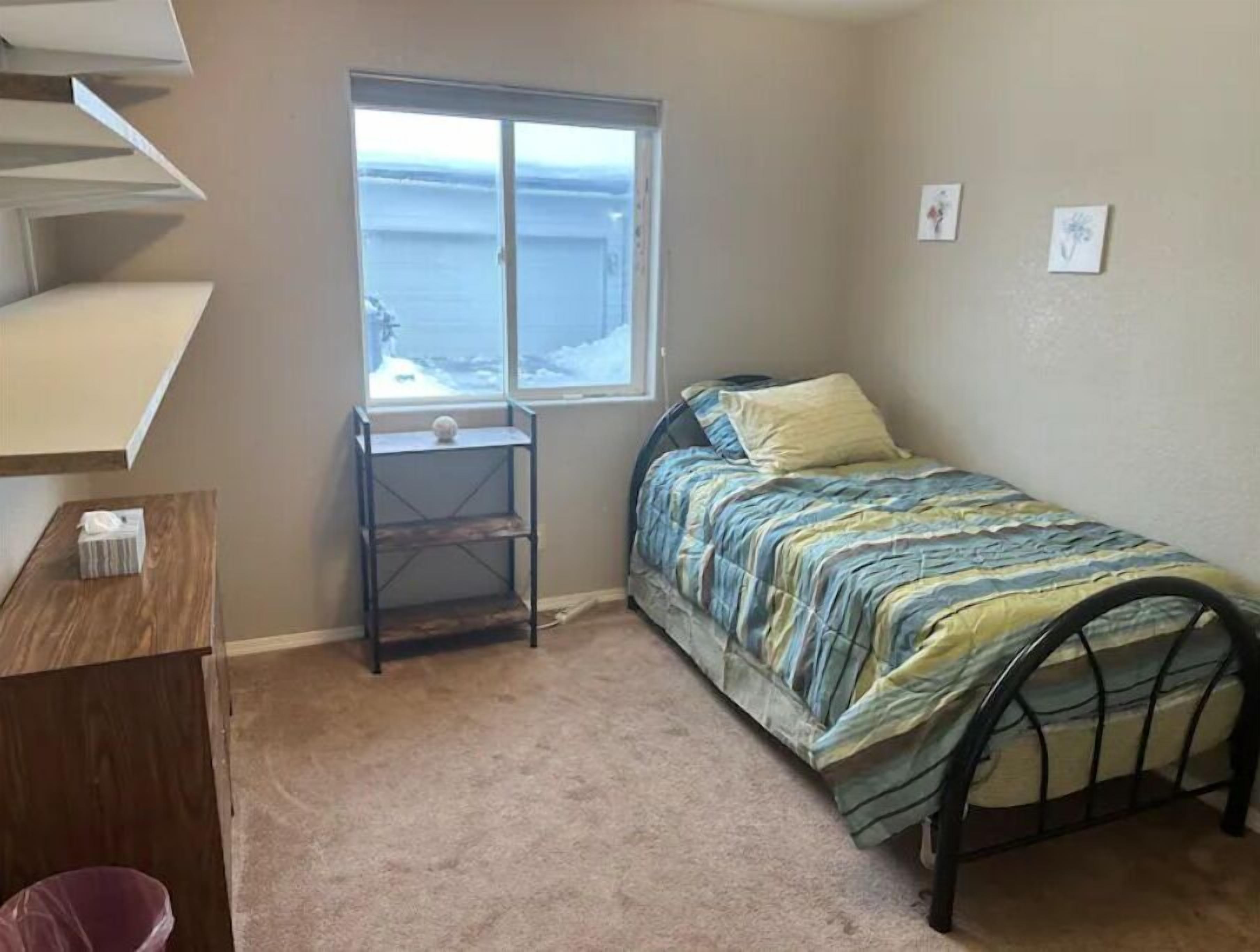 Een slaapkamer met een bed, een klein bureau, een raam met uitzicht op de oceaan en een vloerbedekking.