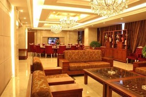 Um saguão de hotel com televisão, área de estar e um candelabro.