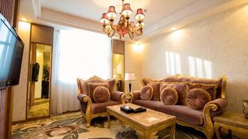 A room with a sofa, a coffee table, a TV, and a chandelier.