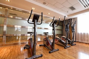 A gym with stationary bikes and a wooden floor. - Wuzhou International Hotel (Shenmu)