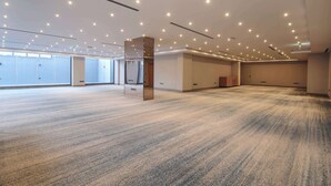 Ein geräumiger, gut beleuchteter Konferenzraum mit Teppichboden, großen Fenstern und einem modernen Deckenstil.