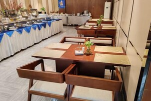 Un comedor con varias mesas y sillas, una barra de buffet y una cocina al fondo.
