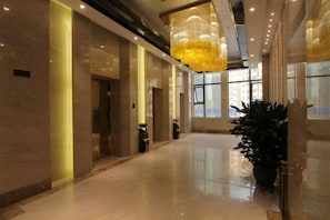 A spacious lobby with a high ceiling, a large chandelier, and a potted plant. - Fuli Hotel (Fushun)