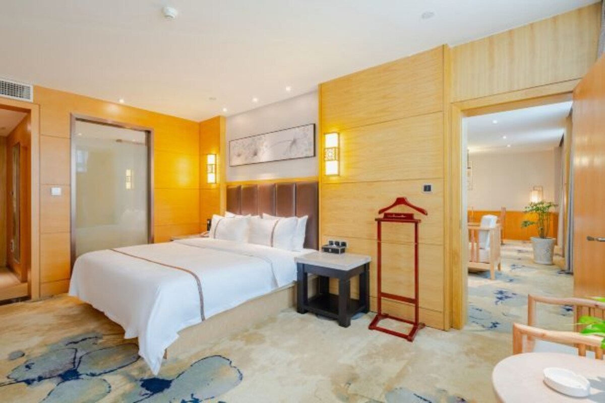 A hotel room with a bed, bedside table, and a small table with a chair.