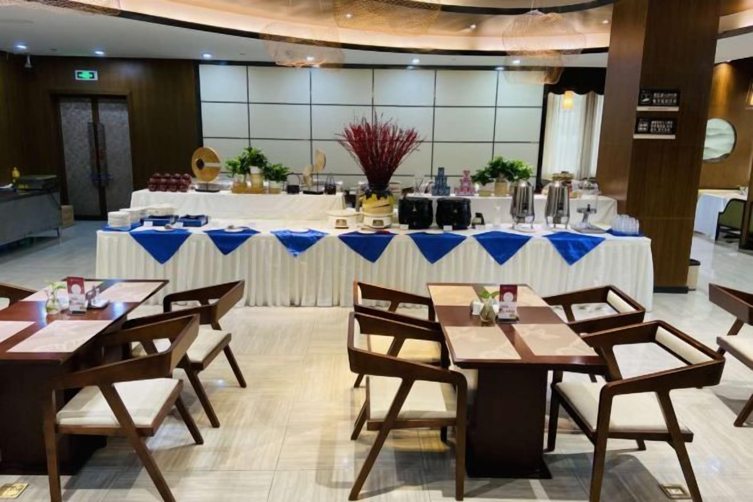 Un salón de banquetes con mesas dispuestas para una comida, una zona de bufé con comida y bebidas, y una decoración central.