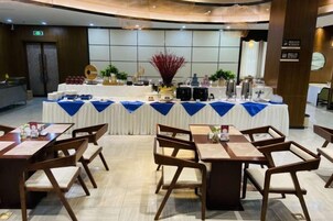 Un salón de banquetes con mesas dispuestas para una comida, una zona de bufé con comida y bebidas, y una decoración central.