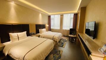 Habitación de hotel con dos camas, televisión, escritorio y ventana con cortinas.