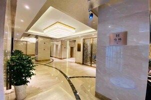 Un vestíbulo de hotel con piso de mármol pulido, una planta en maceta y un letrero con caracteres chinos.