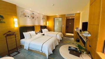 A hotel room with two beds, a round table, a TV, and a wall-mounted shelf.