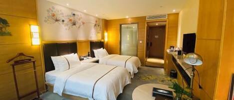 A hotel room with two beds, a round table, a TV, and a wall-mounted shelf.