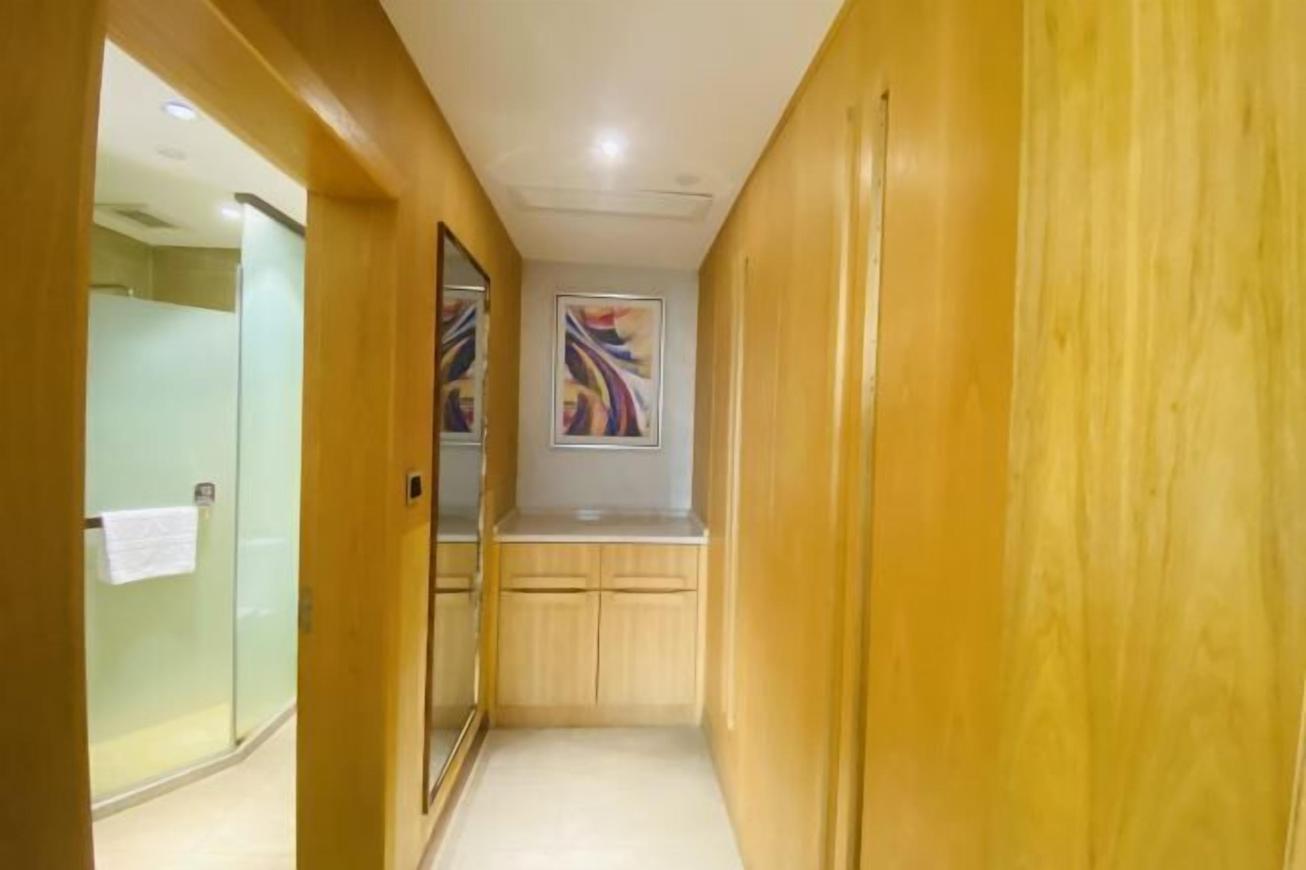 A narrow hallway with wooden paneling and a glass shower enclosure.